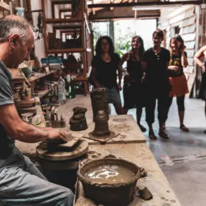 Vasaio crea ceramiche, spettatori osservano.