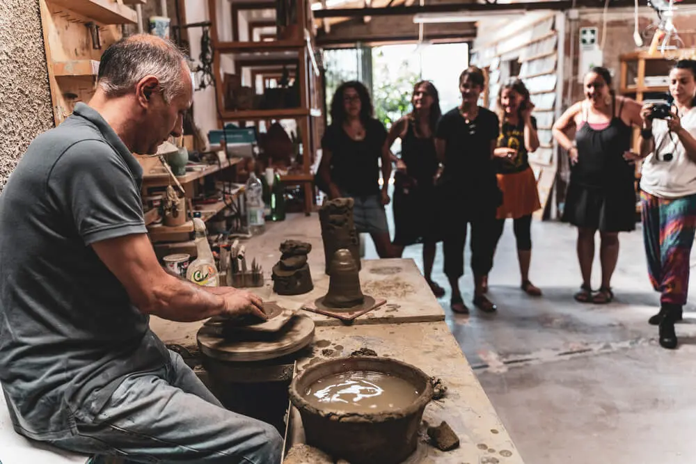 Vasaio crea ceramiche, spettatori osservano.