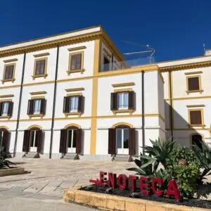 Grande edificio bianco con finestre scure, insegna "Enoteca".