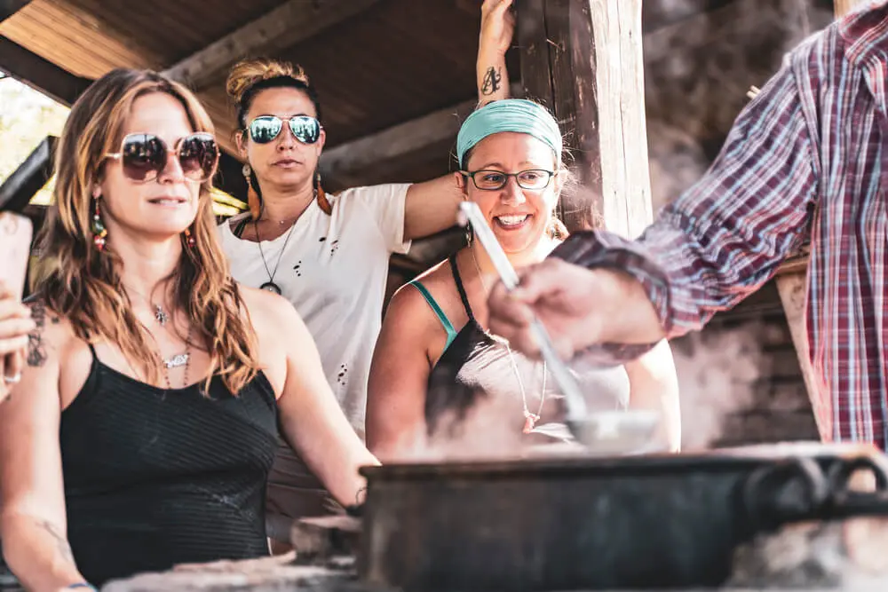 Quattro donne preparano cibo fumante all'aperto.