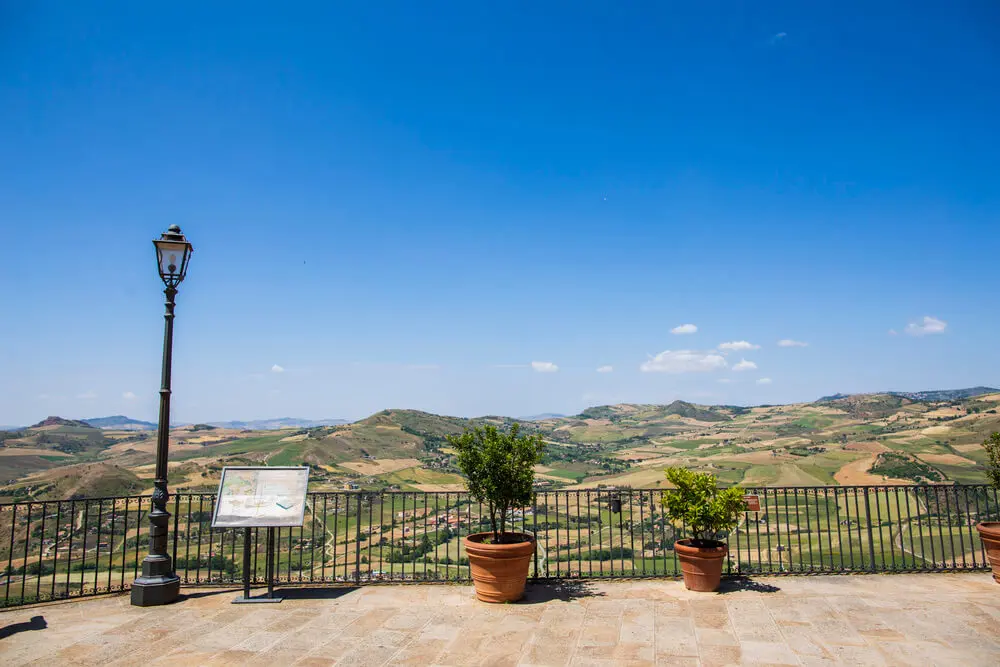 Panoramica collinare, lampione, piante in vaso, cartello.