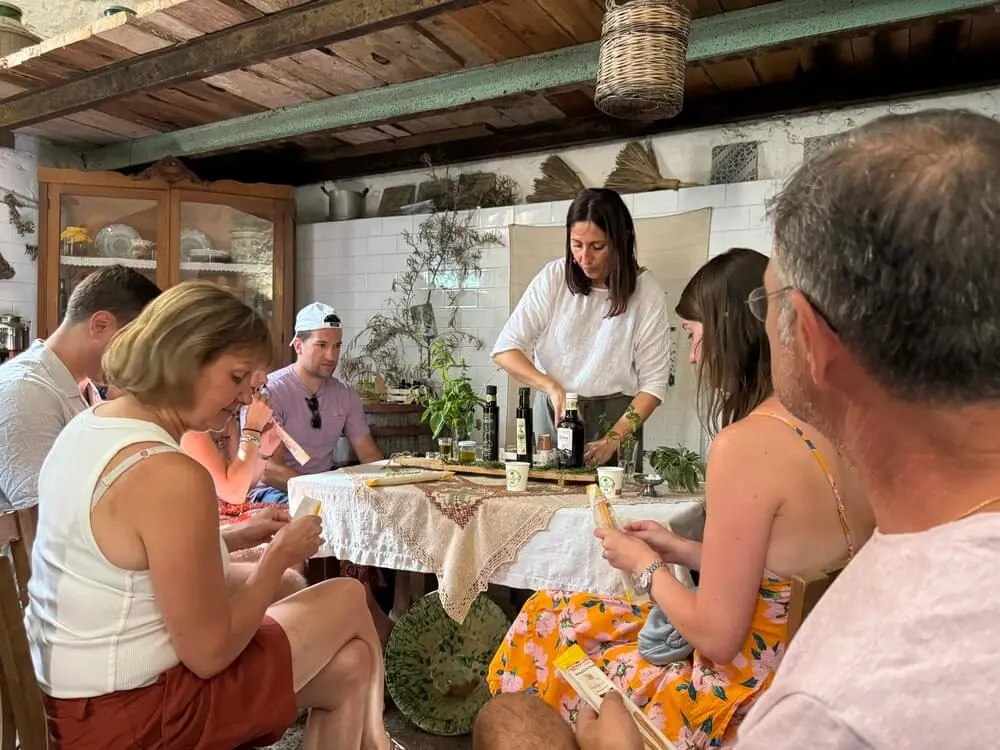 Gruppo assaggia oli d'oliva in una cucina rustica.
