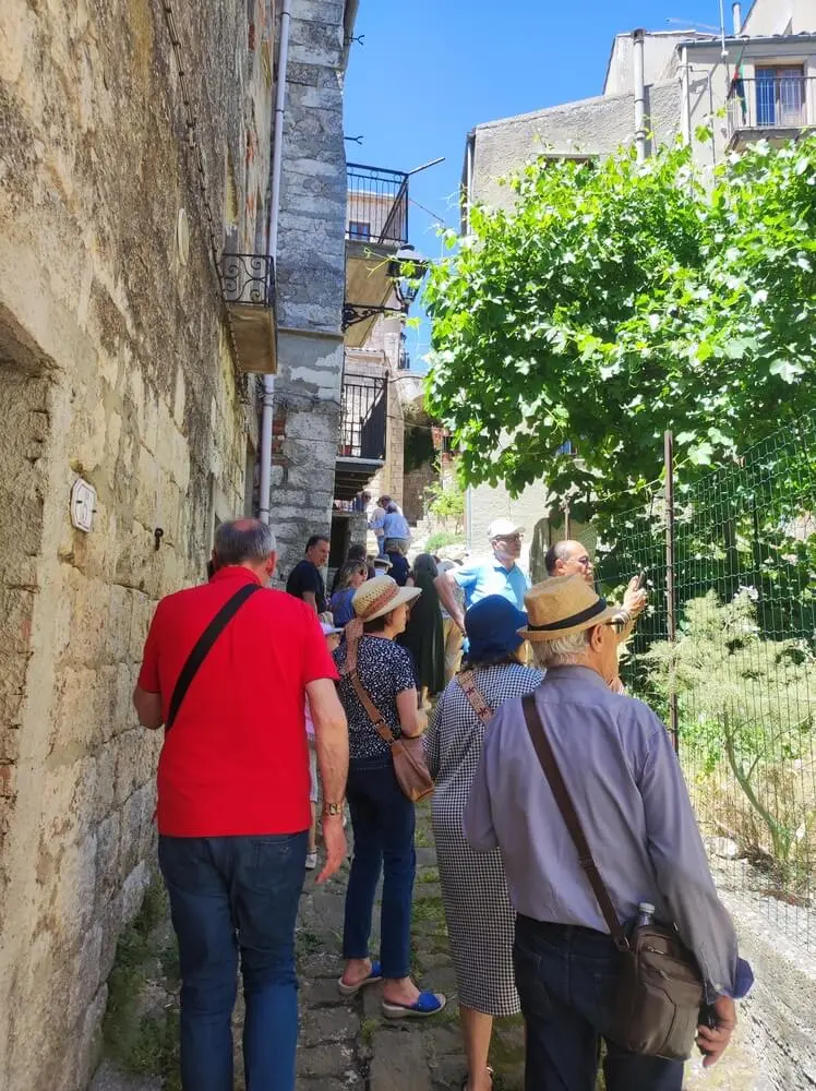 Gruppo di turisti in un vicolo di un borgo antico.