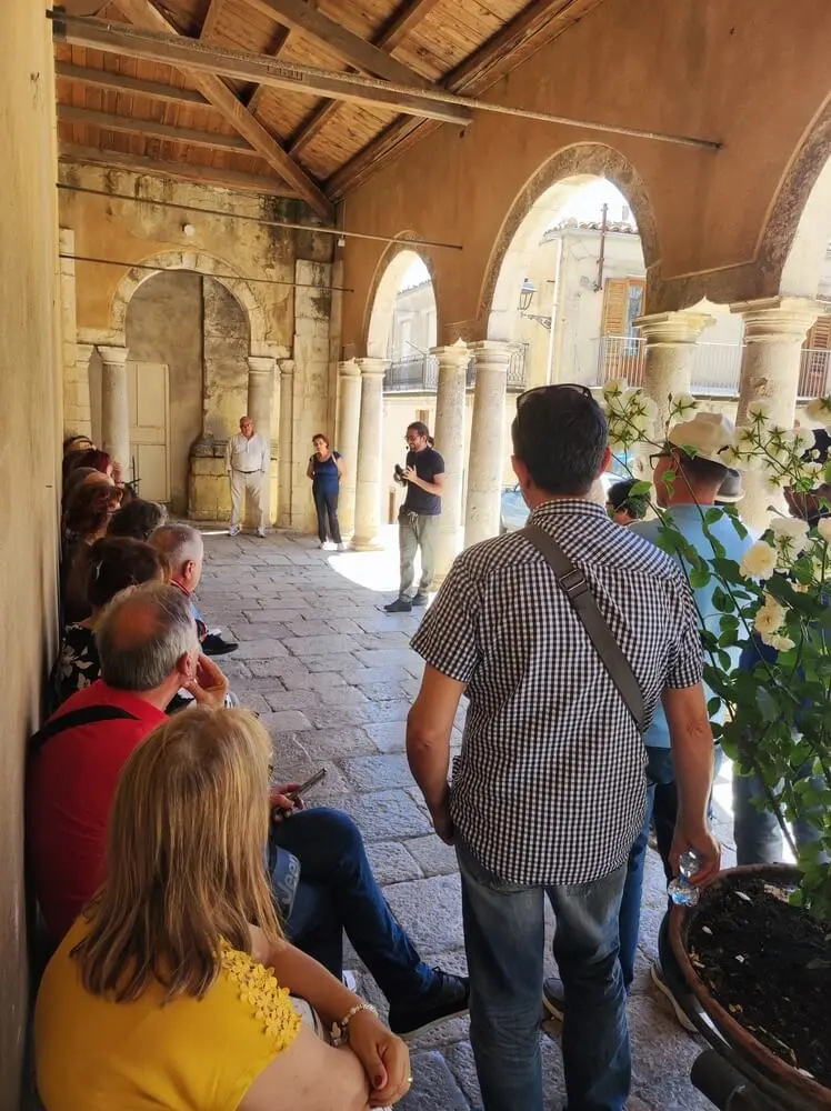 Visita guidata in un portico antico, con colonne e persone.