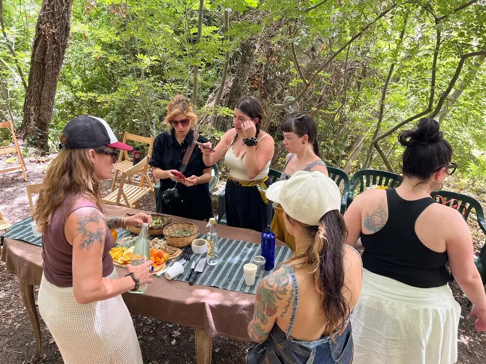 Gruppo di donne prepara cibo all'aperto, bosco.