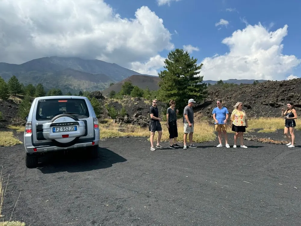 Gruppo di persone vicino a un fuoristrada, sullo sfondo l'Etna.