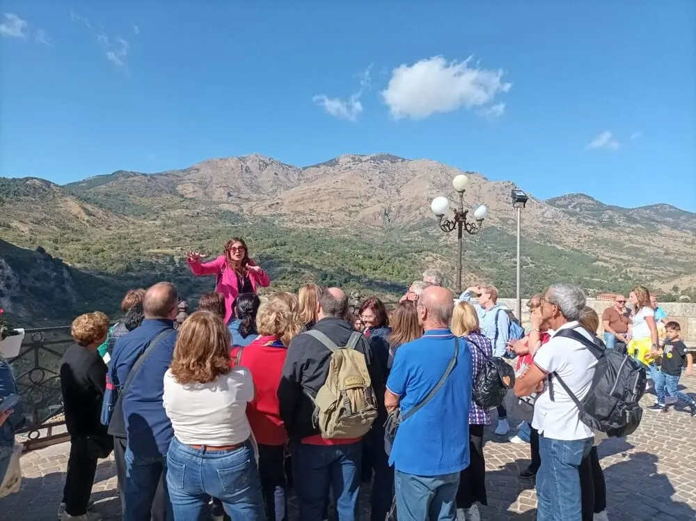 Guida turistica in rosa illustra paesaggio montano a folto gruppo.